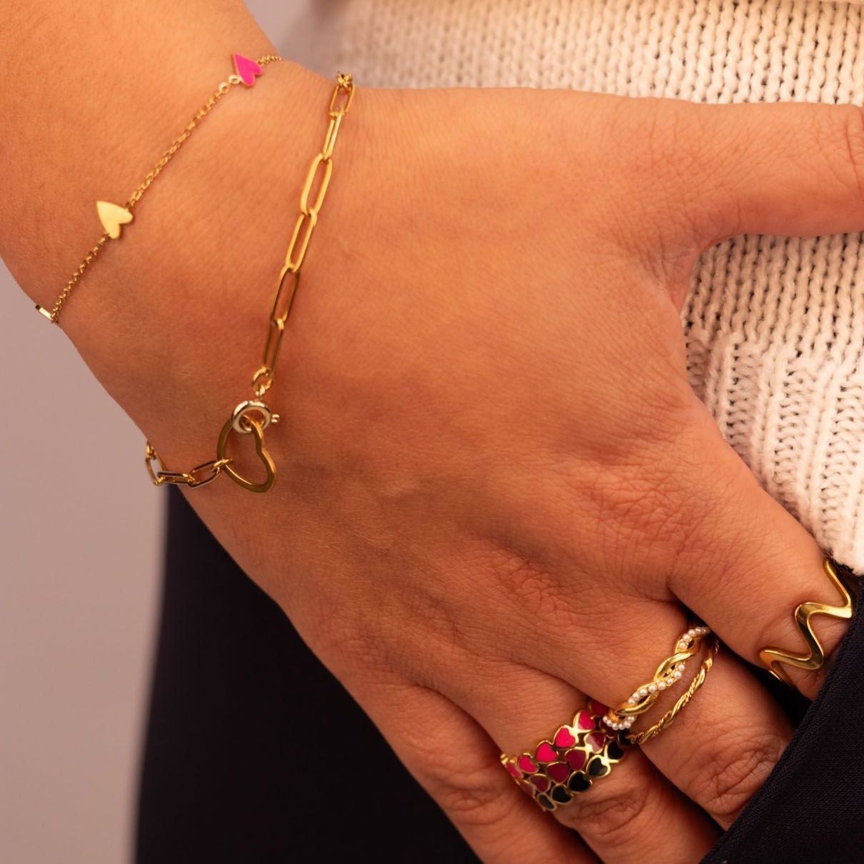 Model draagt een goudkleurig armbandje met open hart, subtiele en speelse toevoeging aan een dagelijkse of elegante look.