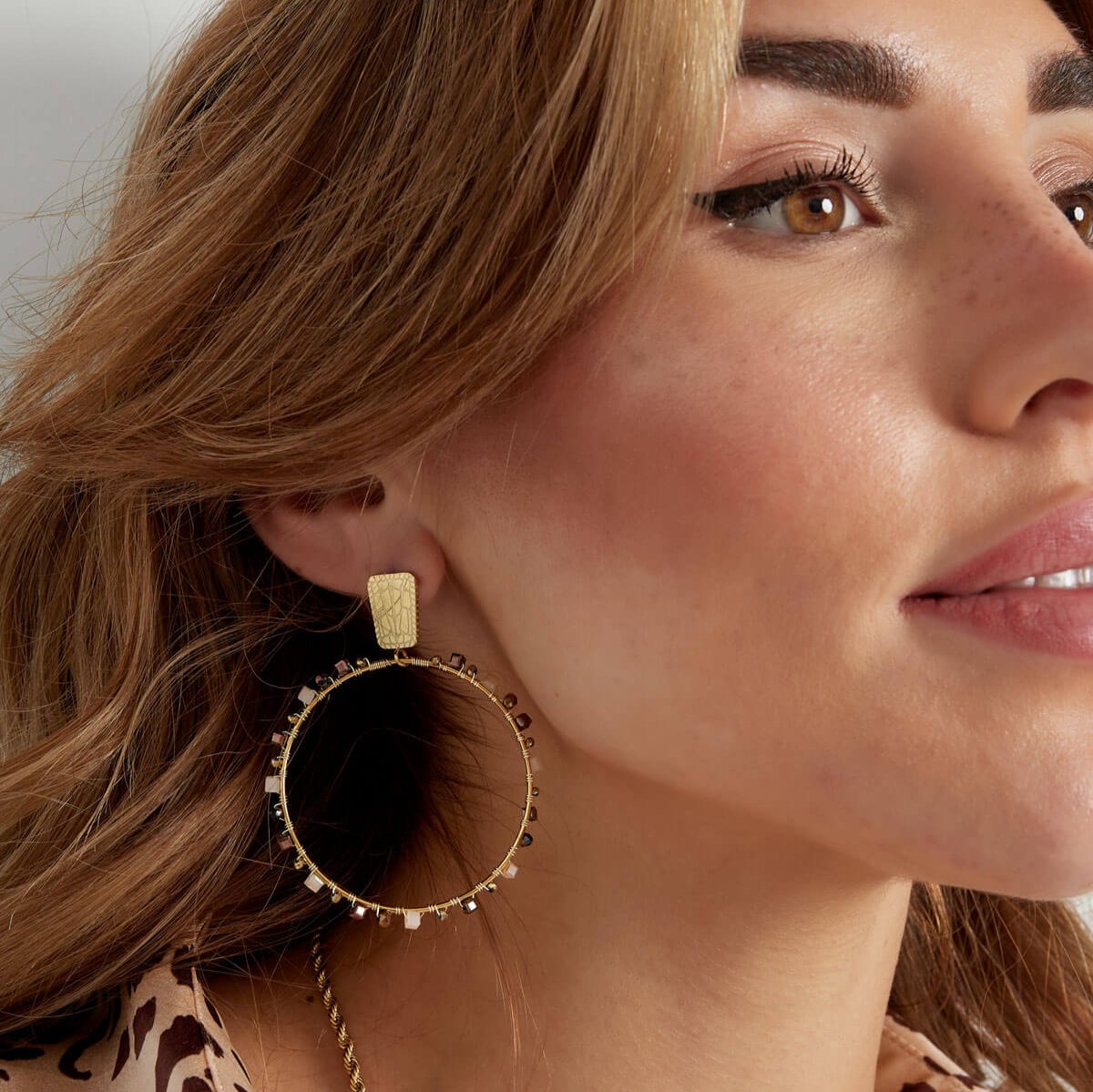 Vrouw draagt Beaded Grace Hoops in beige – statement oorbellen met kralen, subtiel en perfect voor elke gelegenheid.