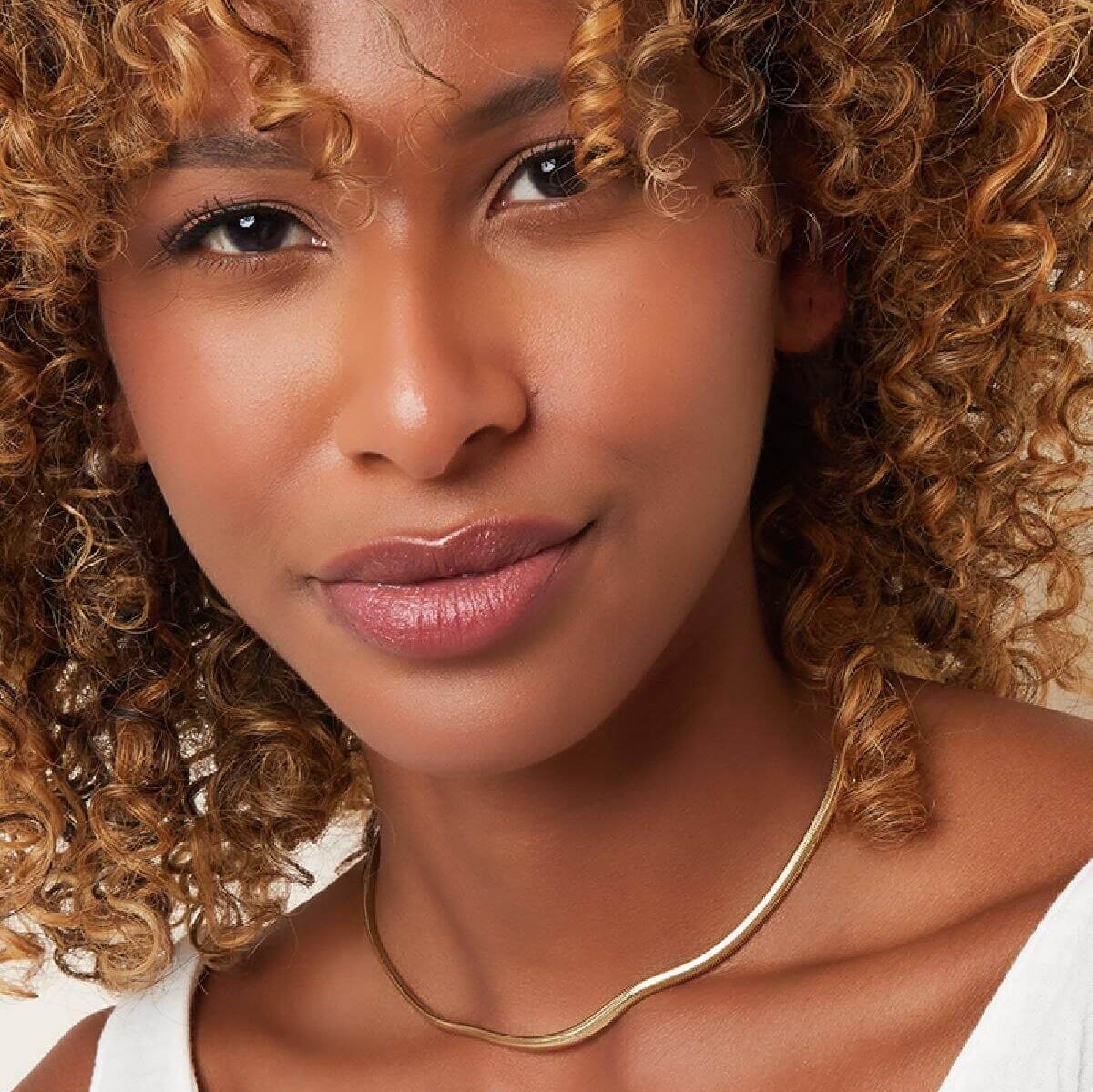 Vrouw draagt The Sleek Snake Ketting goud, minimalistische ketting vrouwelijk en stijlvol.