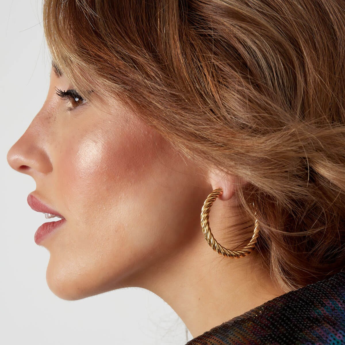 Gouden All Twisted Up Hoops gedragen door model, moderne en nikkelvrije statement oorbellen.