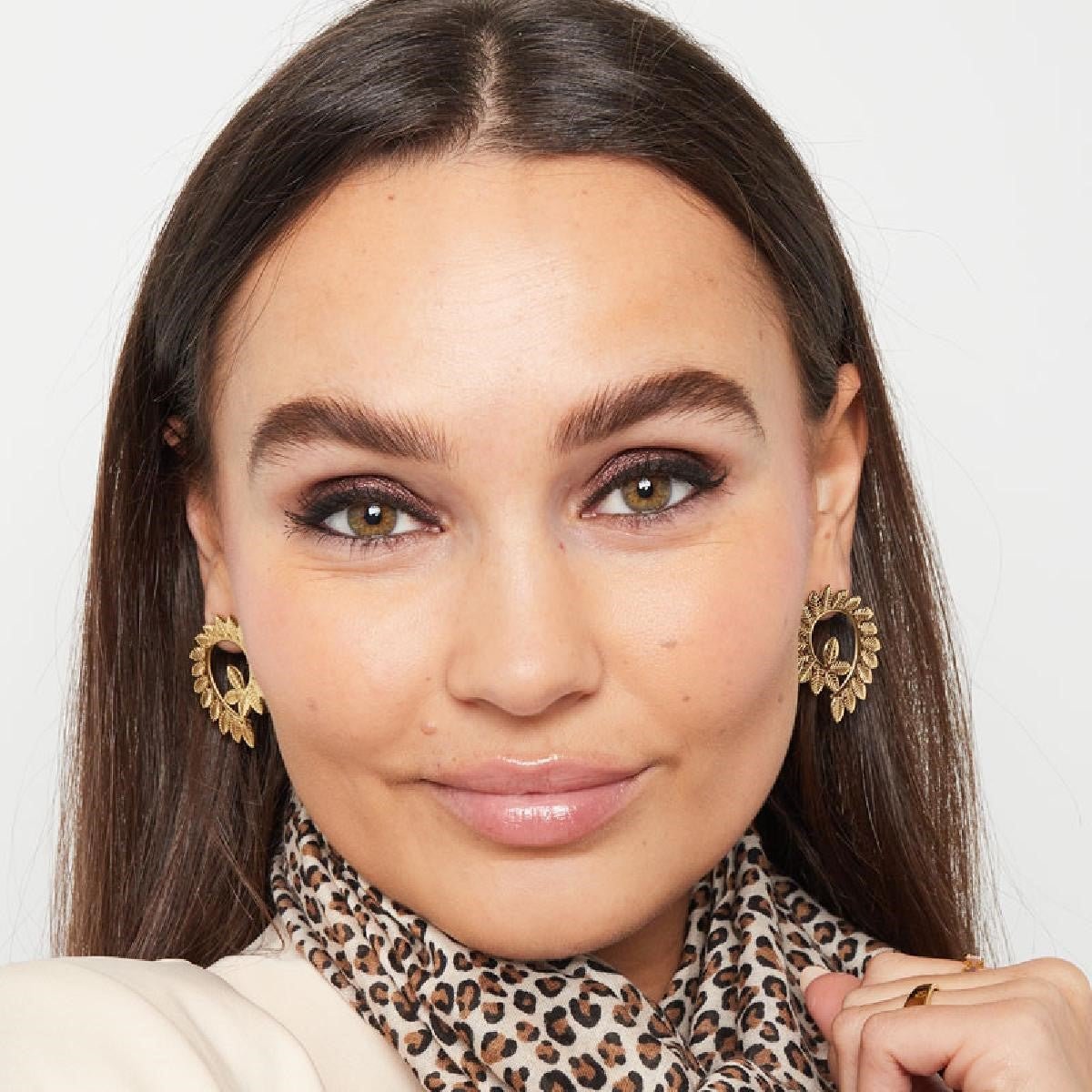 Gouden Leaf Me Be Oorbellen aan het oor van een vrouw – elegante blaadjes oorbellen, perfect te combineren met andere sieraden.