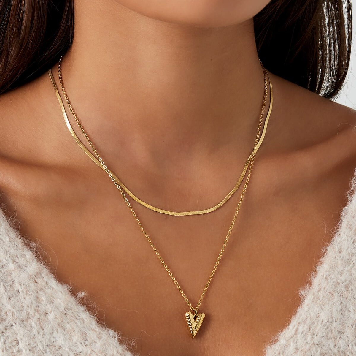 Model draagt gouden dubbele ketting met hart bedel en snake ketting – verstelbare laagjes ketting