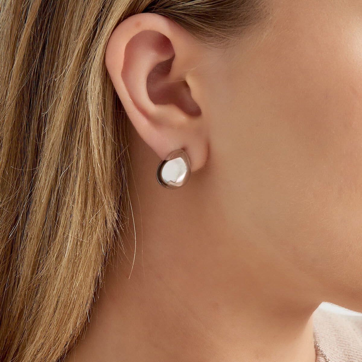 Vrouw met zilverkleurige druppel oorbellen, elegant en classy in roestvrij staal.