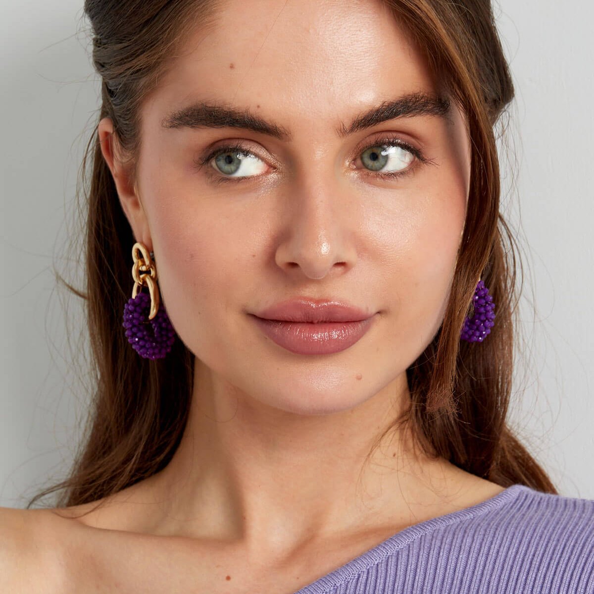 Model met paarse oorbellen - Golden Bond Beads voor vrouwen.