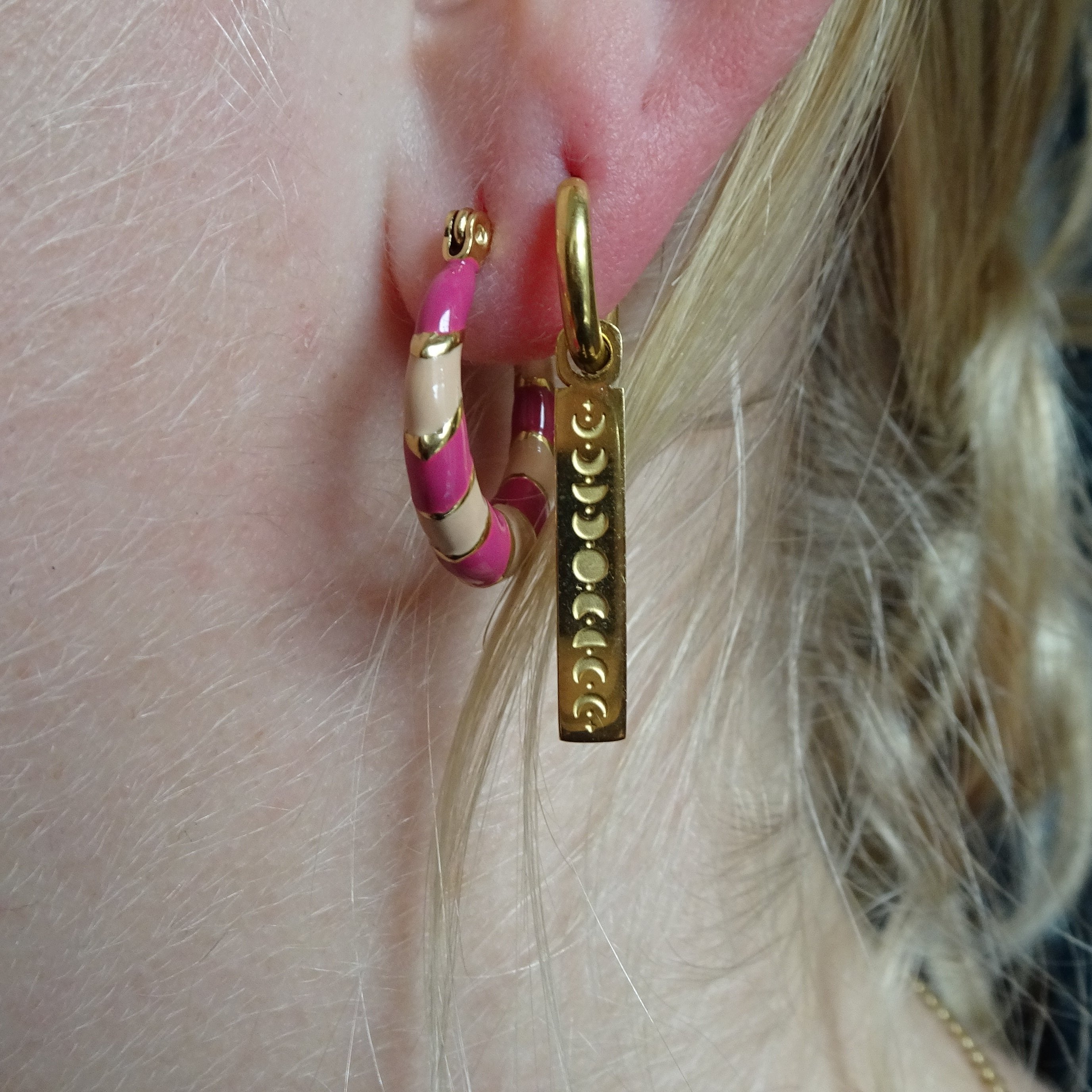 Celia draagt gekleurde creolen in het roze en oorbellen maanstanden bedel: Model Celia draagt onze roze creolen en oorbellen met een charmante maanstanden bedel. Perfect voor een trendy look.