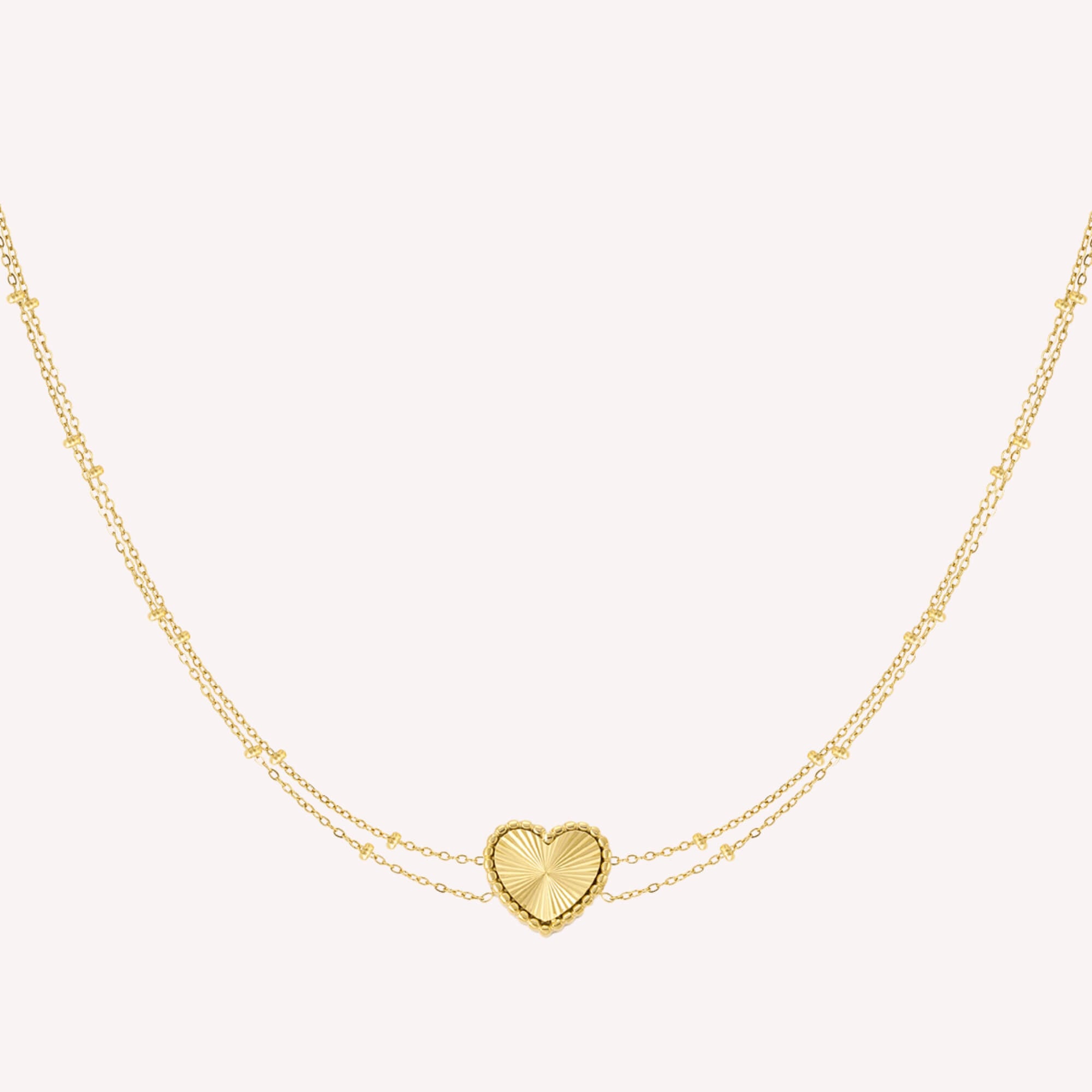 Stijlvolle gouden dubbele ketting met een hartvormige bedel en sunrise-patroon.