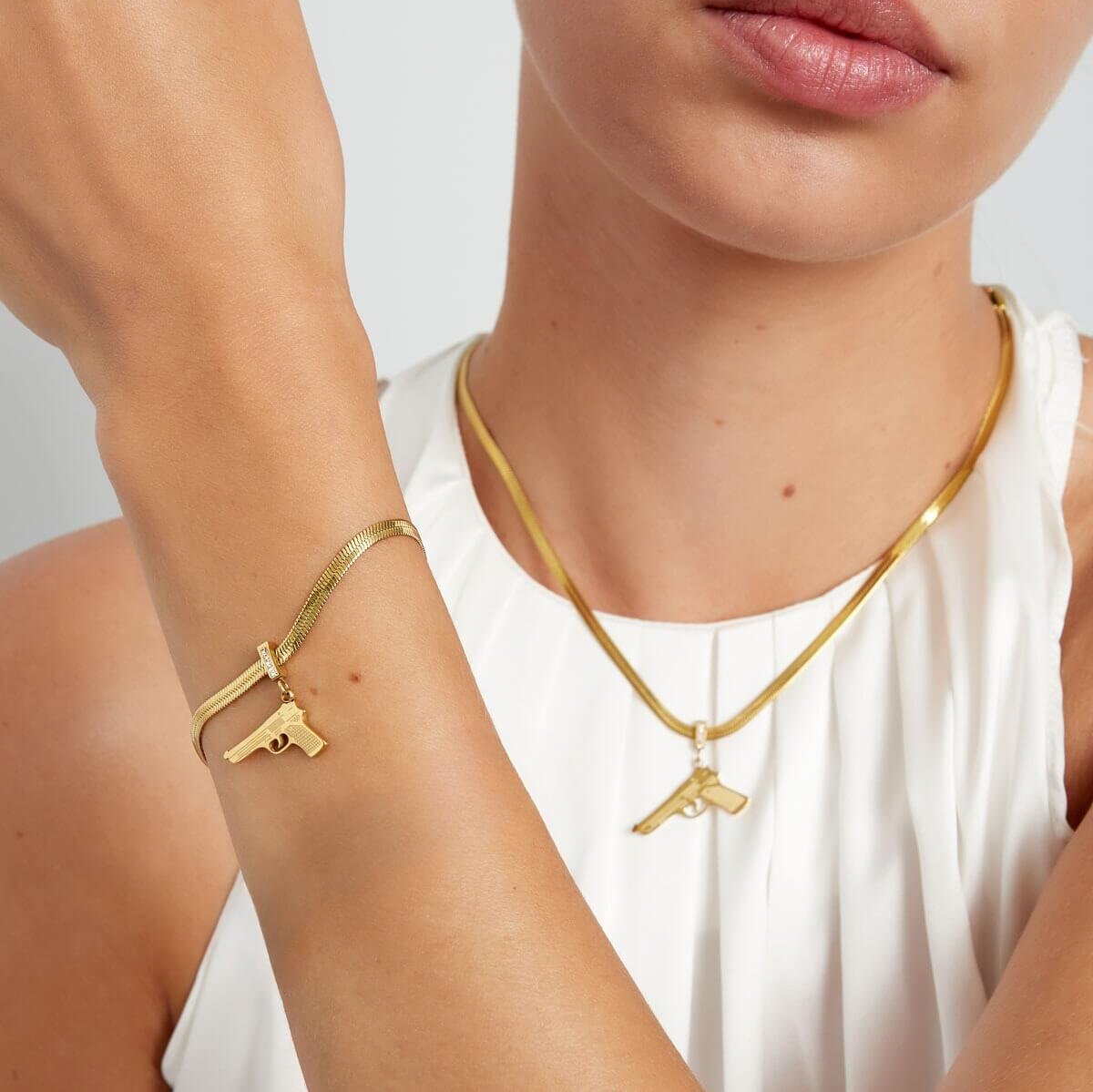 Gouden pistool armband en pistool ketting gedragen door model