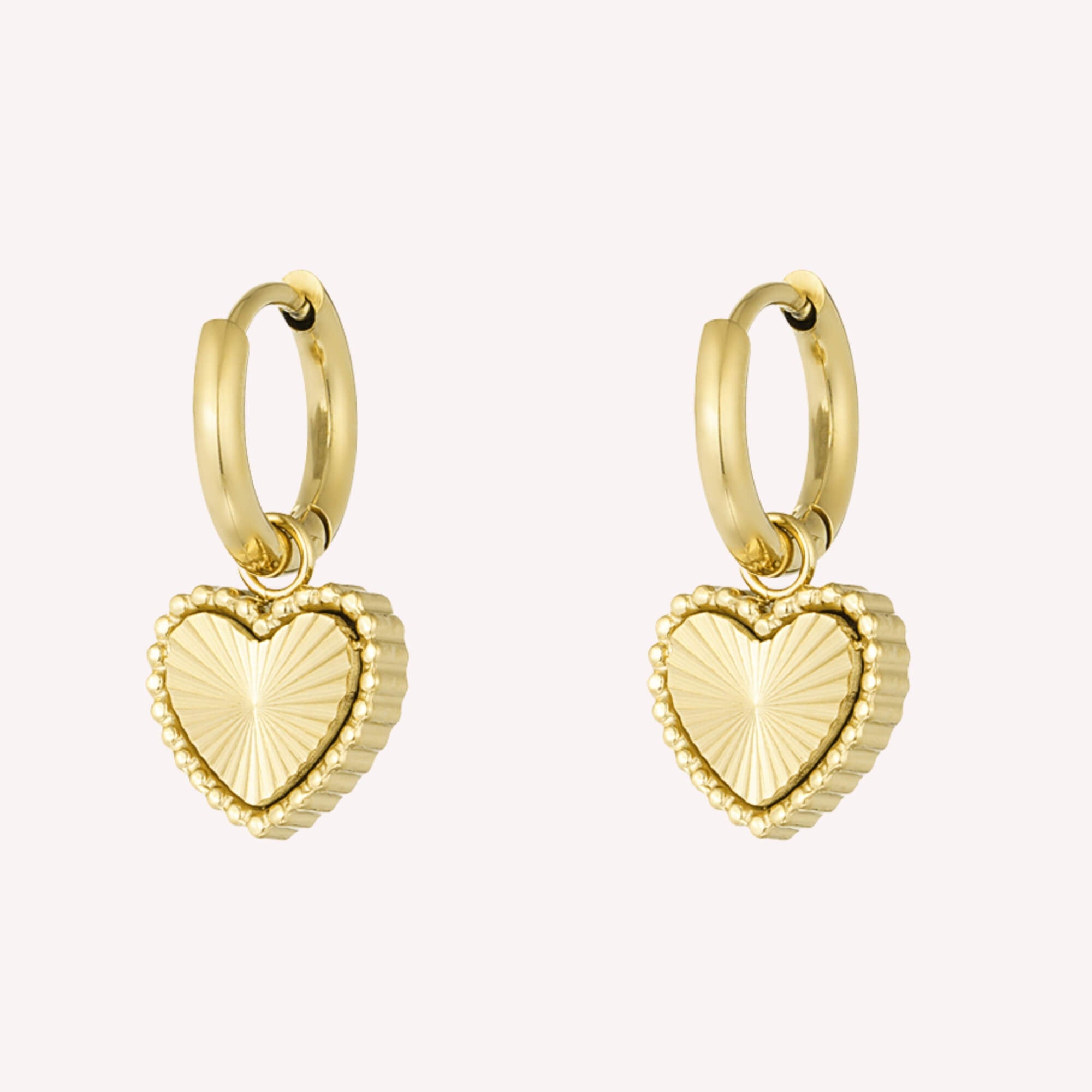 Goudkleurige oorbellen hartjes met streepjesstructuur en elegante rand, gemaakt van roestvrij staal. Dit zijn de Shine From Within Oorbellen in het goud.