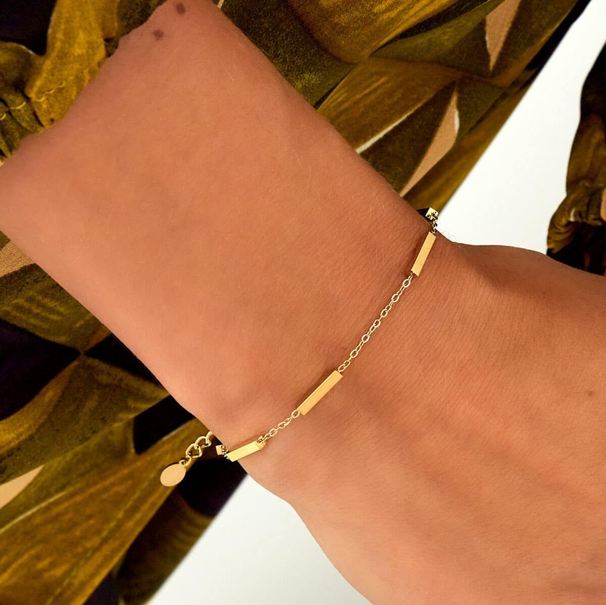 Model draagt gouden minimalistische armband met kokers voor een elegante uitstraling