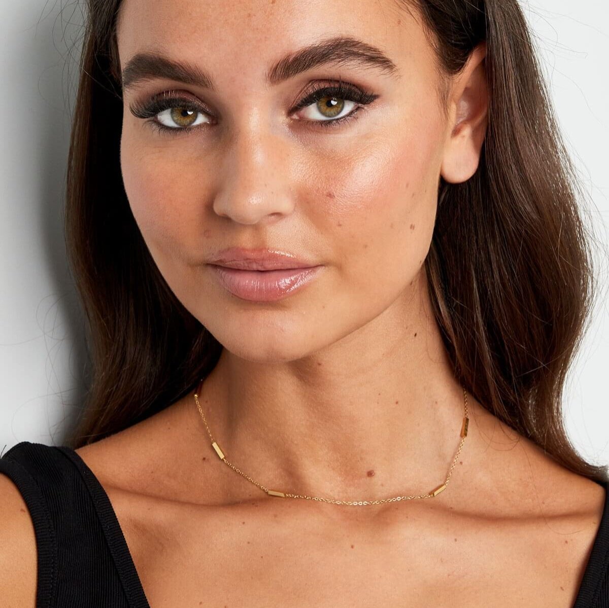 Minimalistische gouden ketting op een vrouwelijk model, een stijlvolle aanvulling voor een tijdloze look.