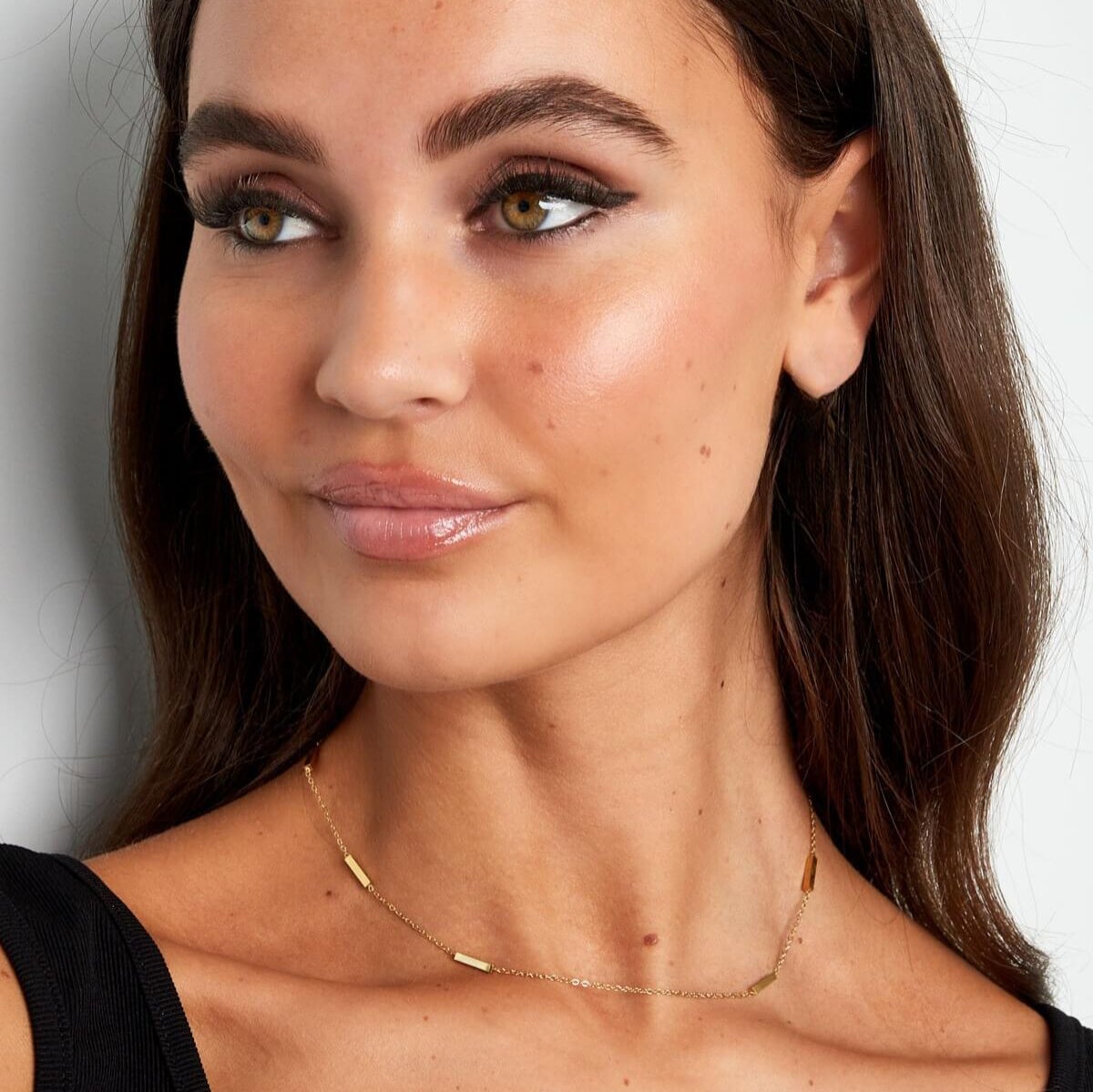 Vrouw met minimalistische gouden ketting, subtiel en perfect voor een elegante en verfijnde uitstraling.