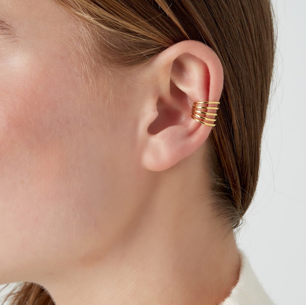 Vrouw draagt The Bold & Beautiful gouden ear cuff, perfect voor een gedurfde look.
