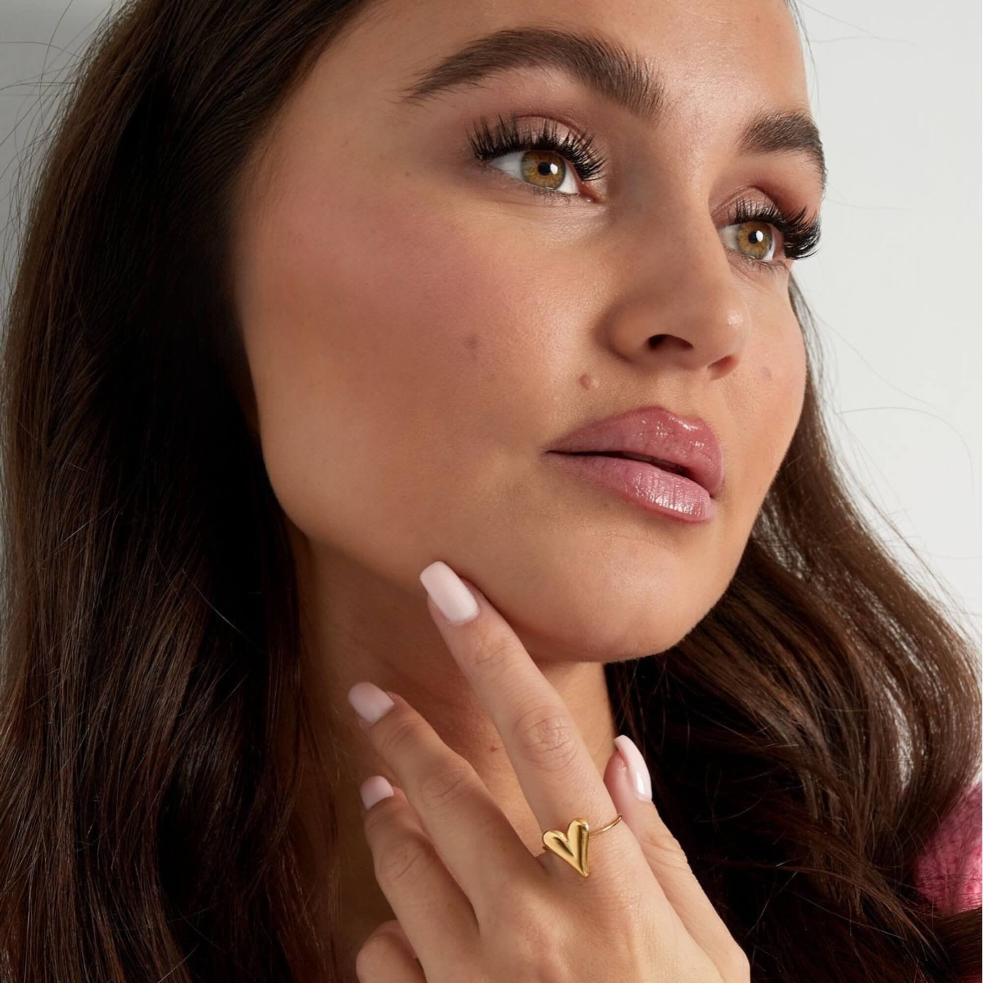 Vrouw draagt de gouden verstelbare ring met een harten bedel, de Wrap Me in Love Ring.