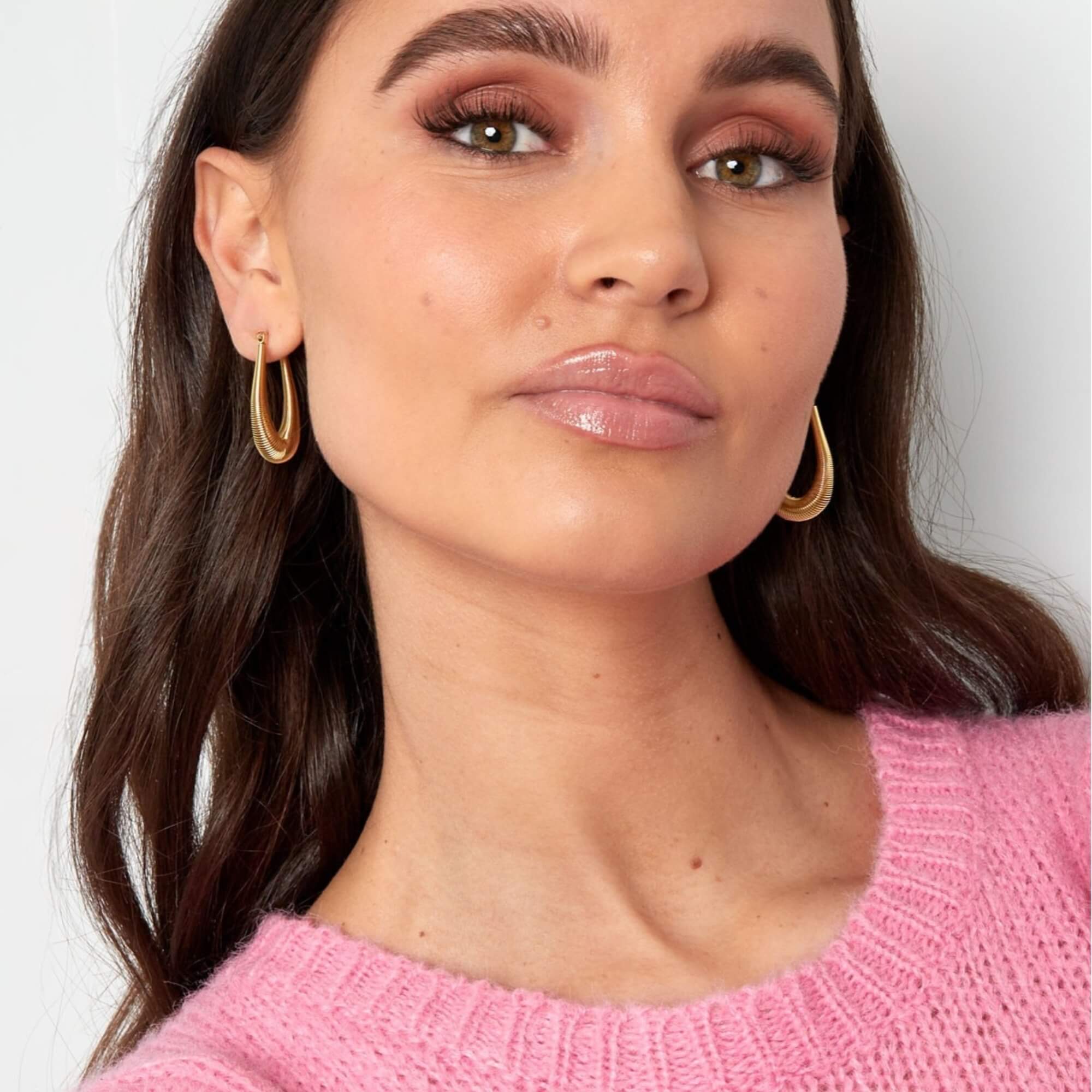 Model showt zilveren Wrapped in Style Oorbellen met subtiel veerelastiek, gemaakt van roestvrij staal.