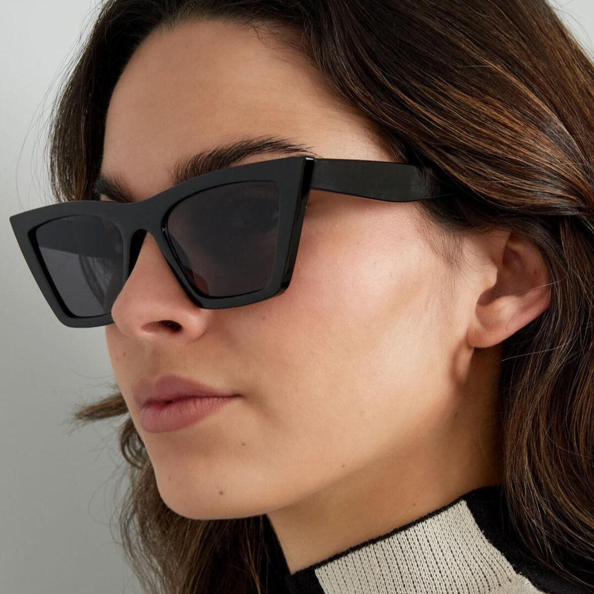Vrouw met zwarte Own the Day Zonnebril. Mooie zonnebrillen dames stijl. Zelfverzekerd & chic voor elke dag of avond.