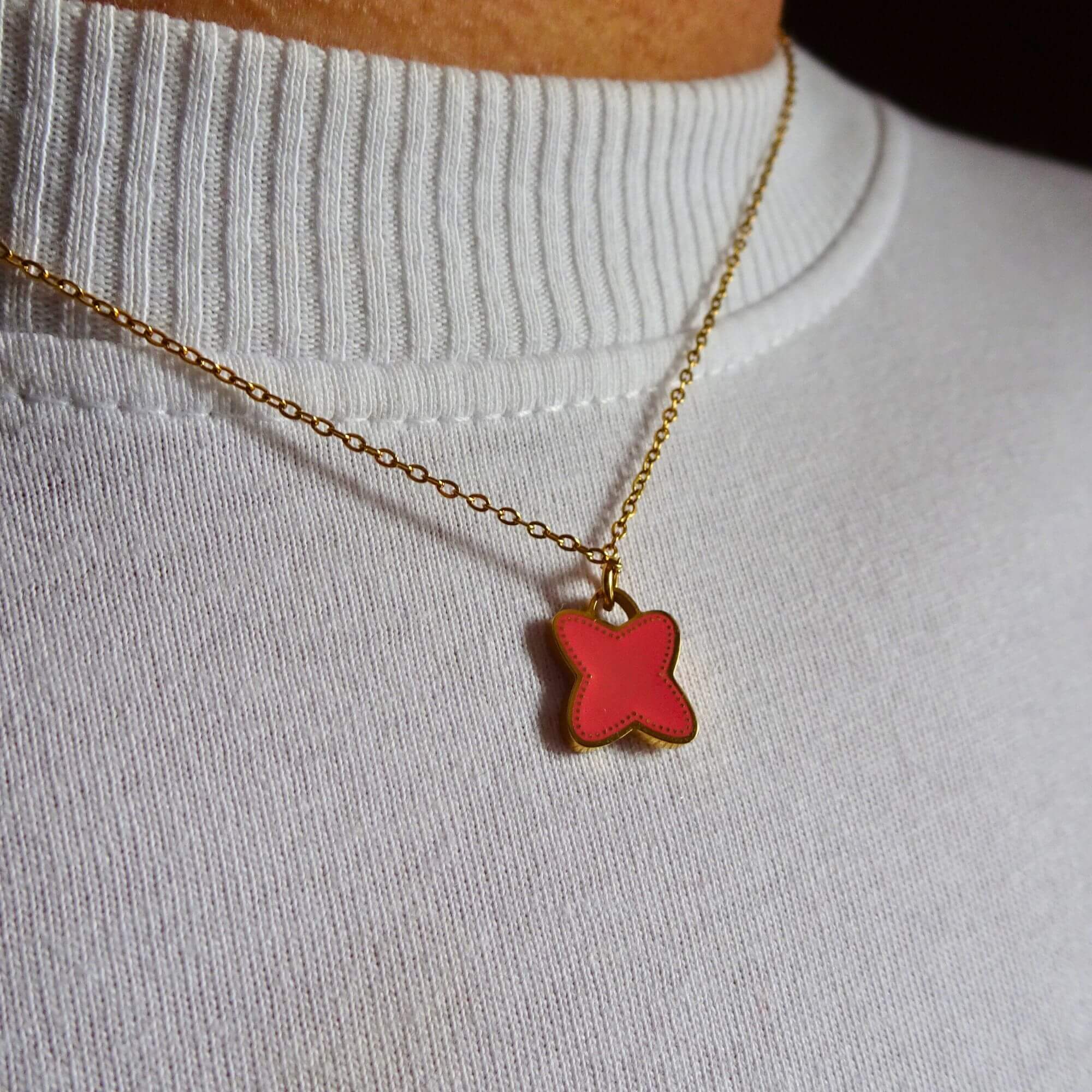Model draagt Lucky Charm Ketting koraal – vrolijke en betekenisvolle ketting met klaverbedel in koraal, geschikt voor dagelijks gebruik en feestelijke looks.