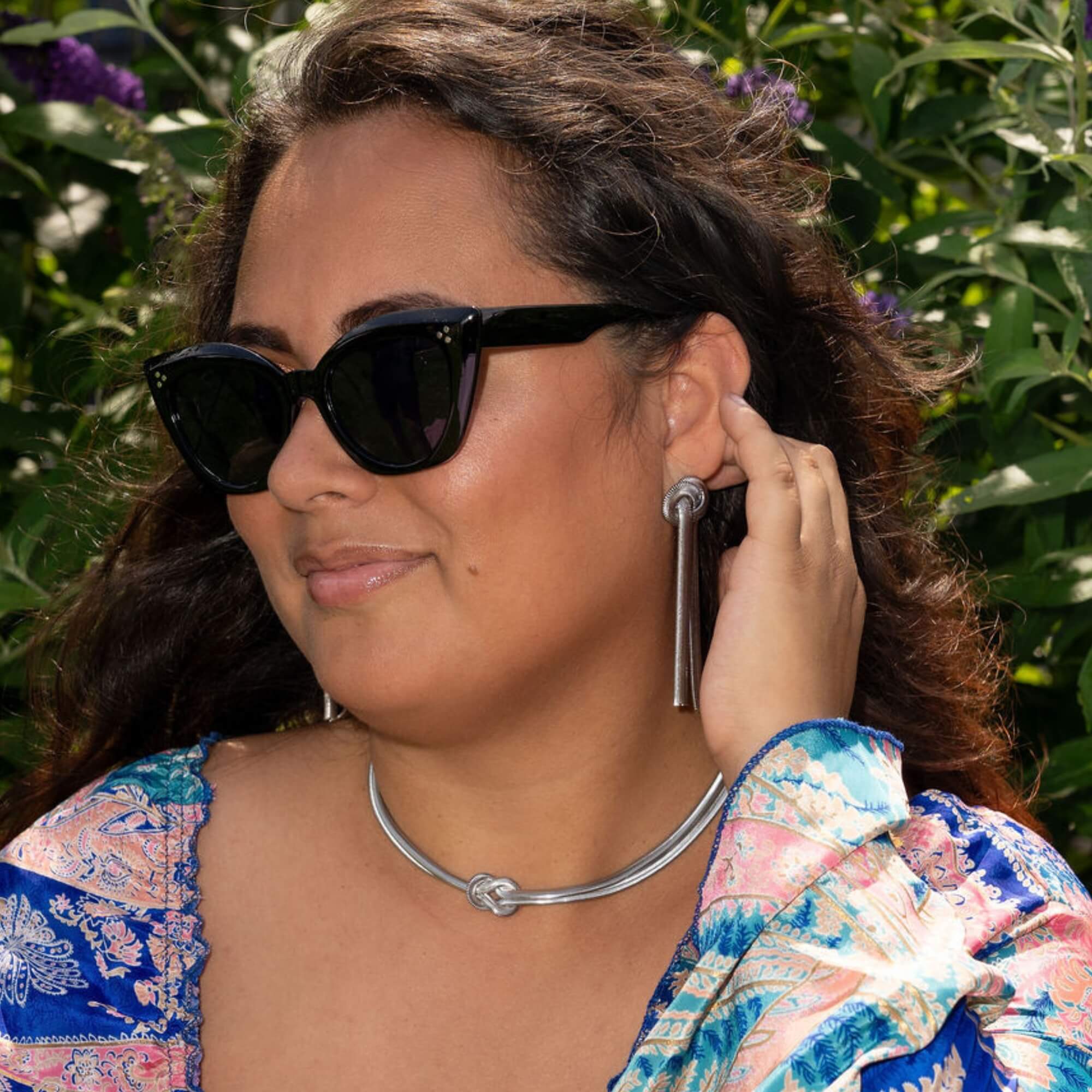 Model draagt de Bound by Beauty Oorbellen in zilver – chique zilveren oorbellen met betekenisvolle knoopvorm, een stijlvol accent voor vrouwen.