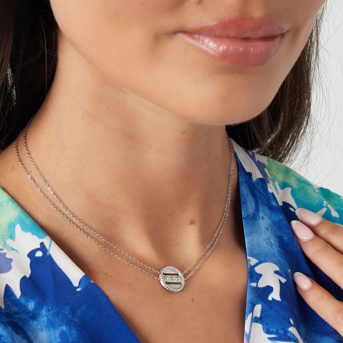 Model met zilveren dubbele ketting en coin bedel. Verfijnde en veelzijdige ketting, perfect voor elke gelegenheid.